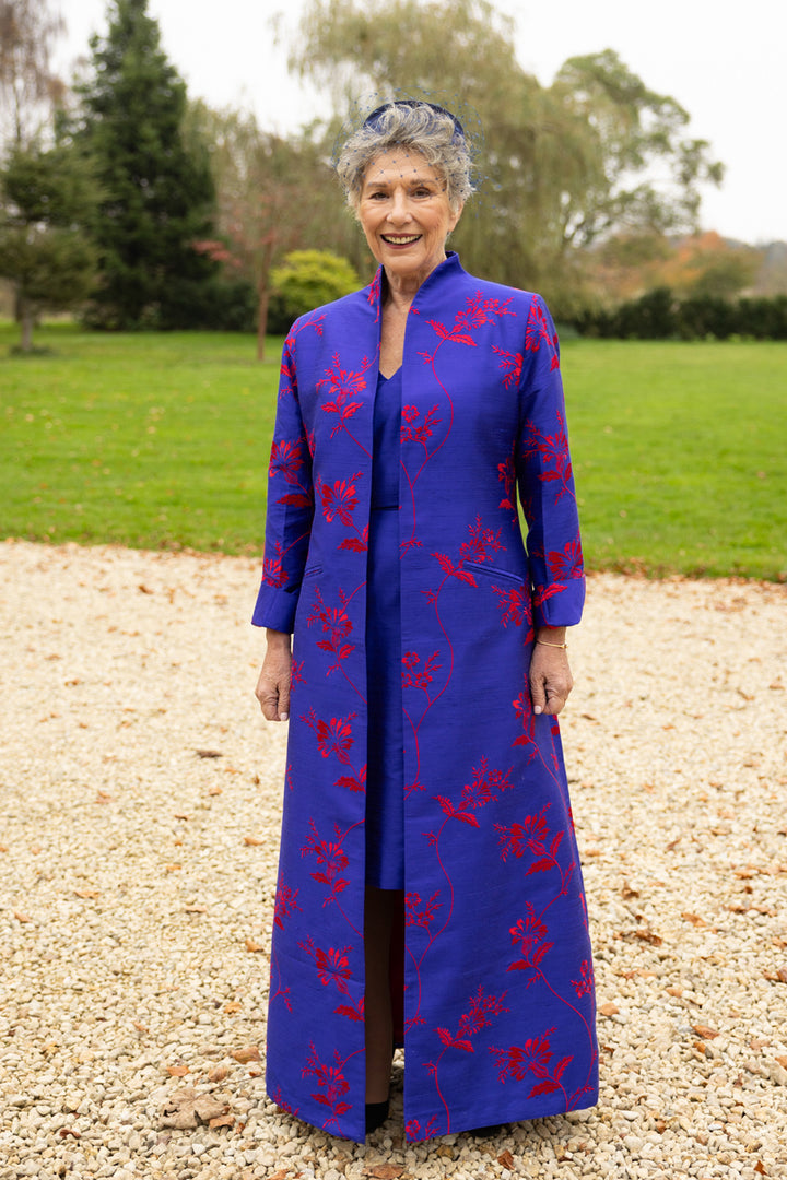 Maxi coat in blue cobalt with large floral embroidery in red. This long ladies coat has a high collar and it is design to be worn open. This would be an amazing mother of the groom coat. 