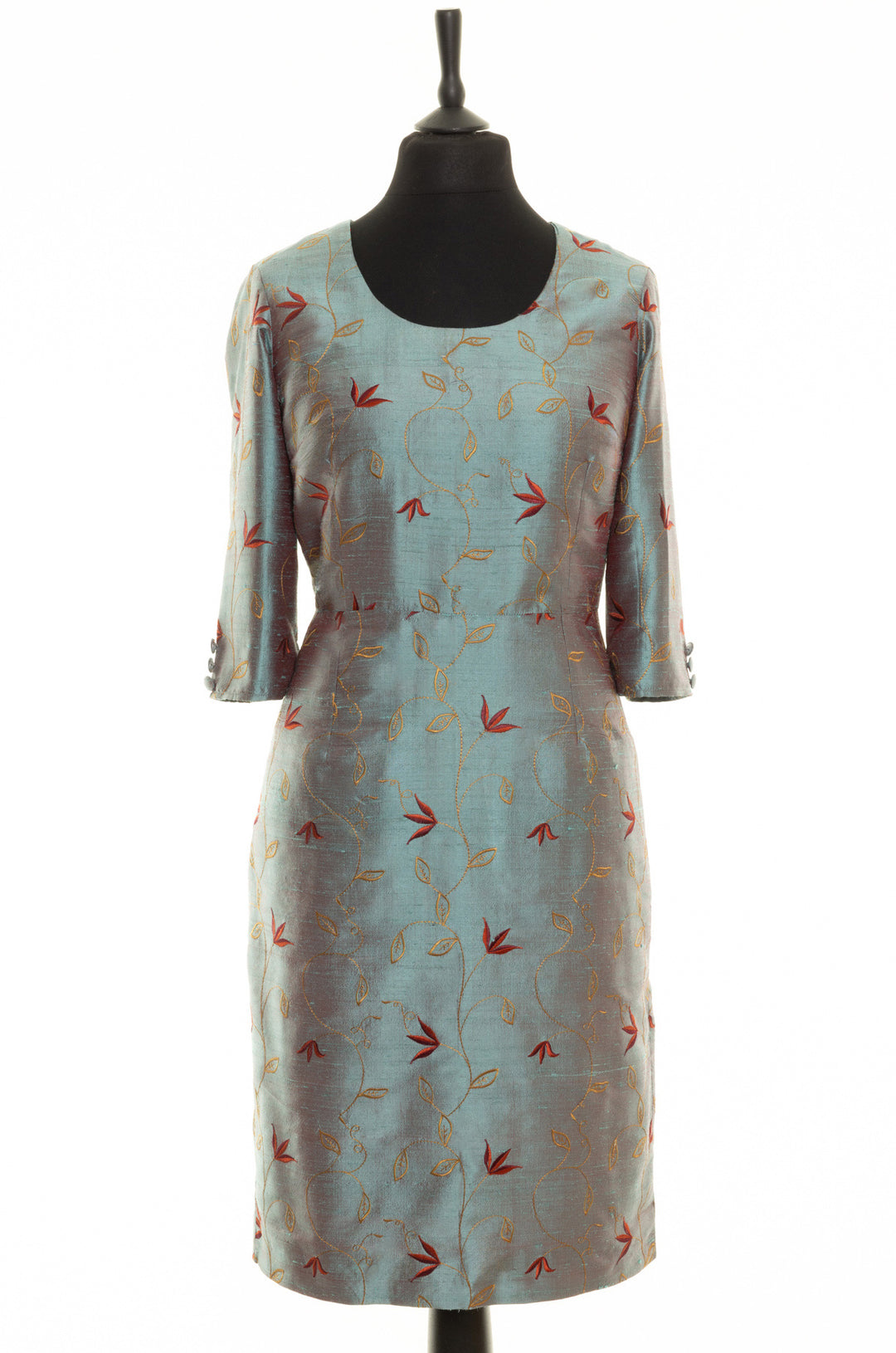 Round neckline dress for women. Smokey blue silk dress with golden and red floral embroidery. This dress has longer sleeves and is knee lengths. There are 3 buttons at the bottom of each sleeve. 