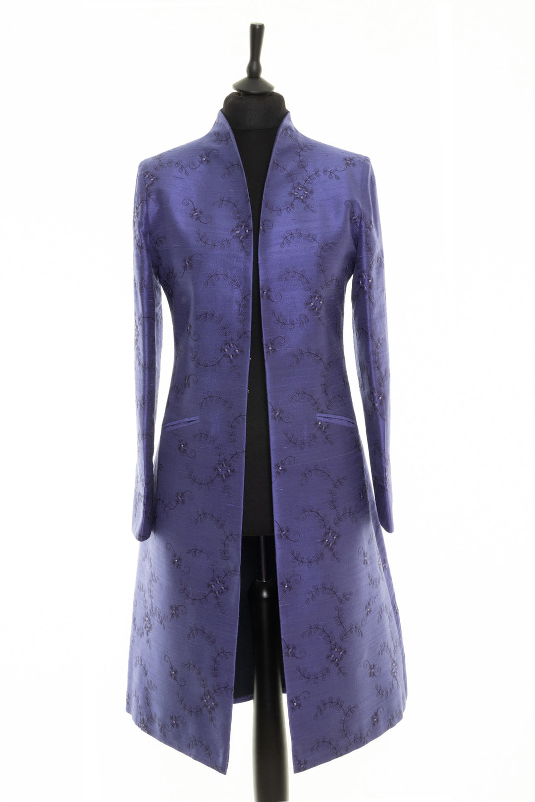 Elegant dress coat in periwinkle by Shibumi. The fabric is silk with embroidery. It has high collar and two pockets. 