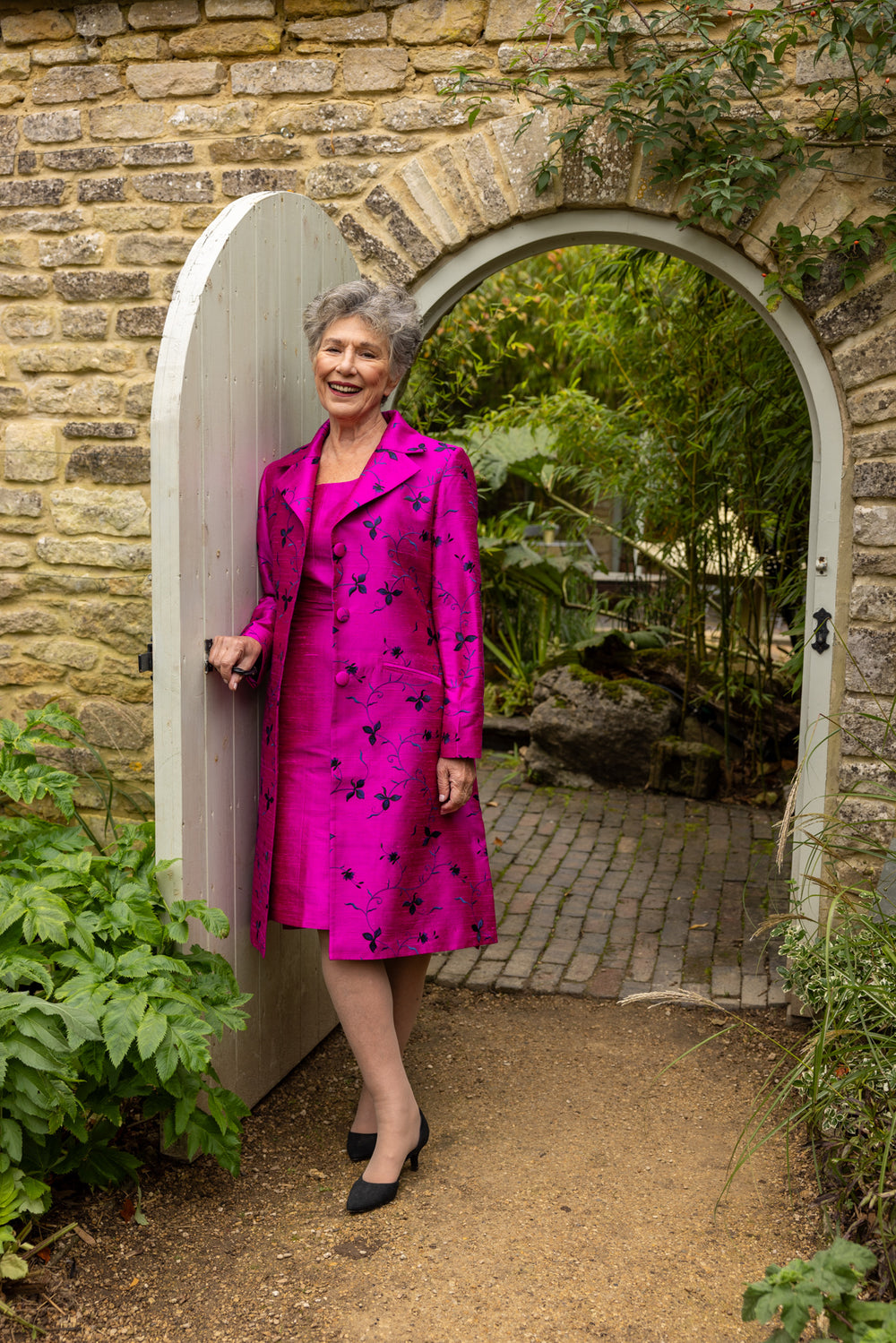 Bright pink coat with floral pattern with patching colour dress. Mother of the bride pink outfit. 