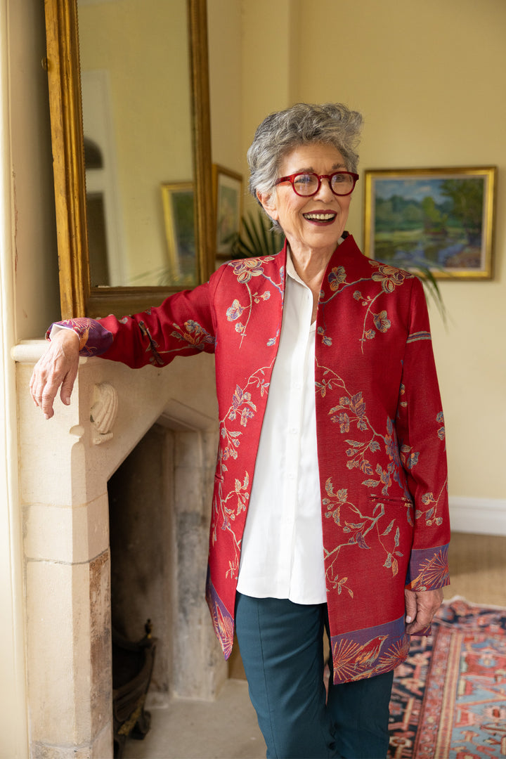 Mature lady wearing a red jacket with floral pattern. Cashmere jacket that can be worn smart or casual. 