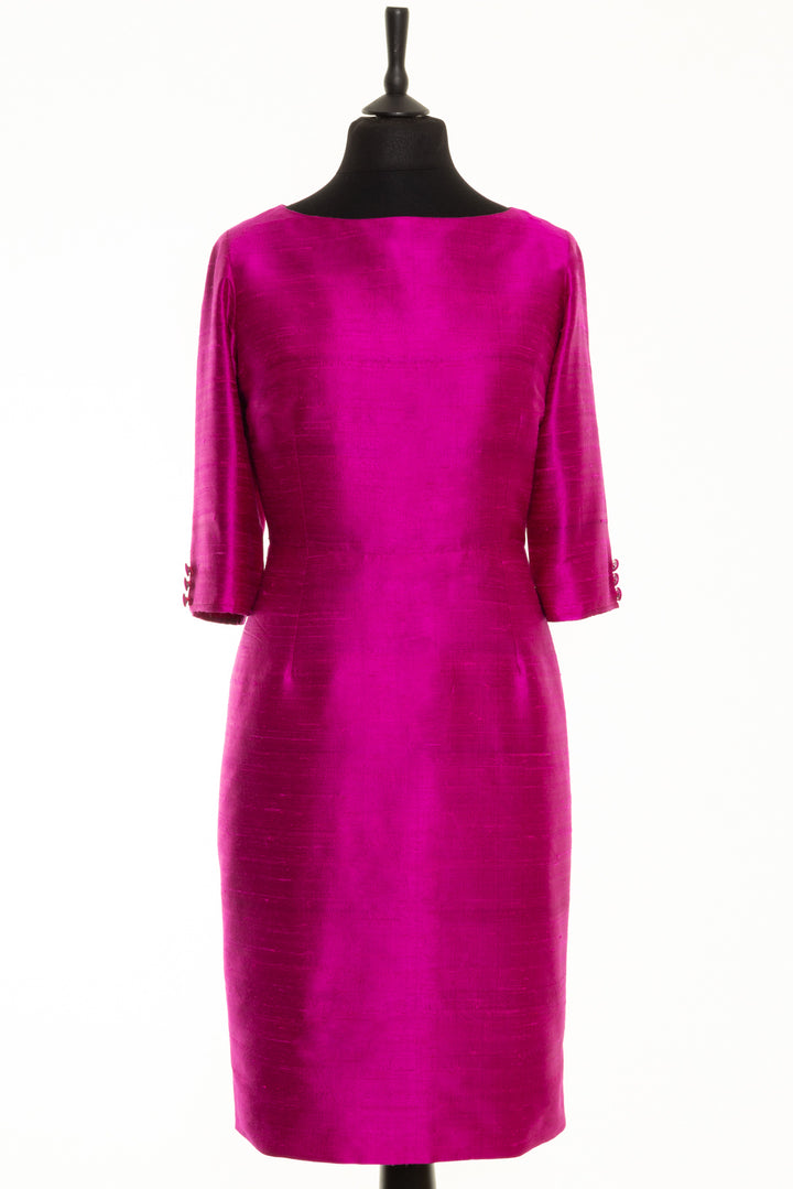 Straight neck silk dress. This dress is bright pink and fitted around the waist. It has longer sleeves with button detail. 