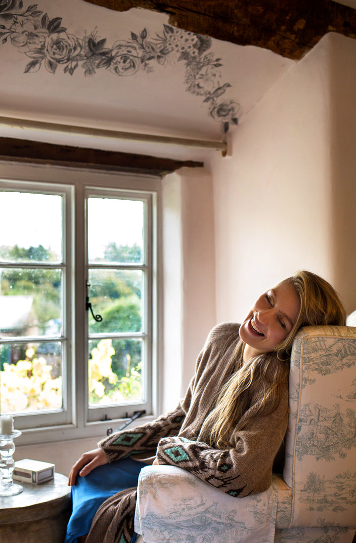 Happy girl in front of a window wearing alpaca cardigan